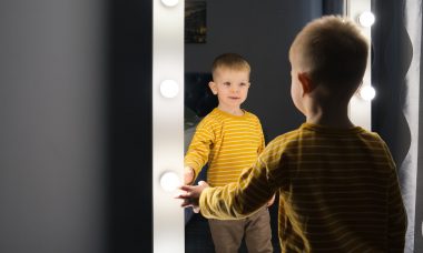 chłopiec w żółtej bluzie przegląda się w lustrze